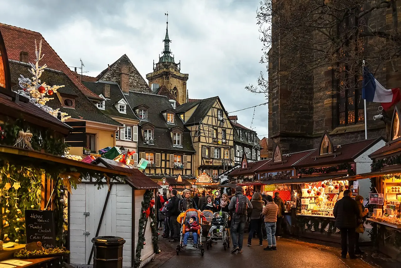 Stalls on Place des Dominicains next to the Dominican church at dusk, the tower of the Saint-Martin collegiate church in the background
