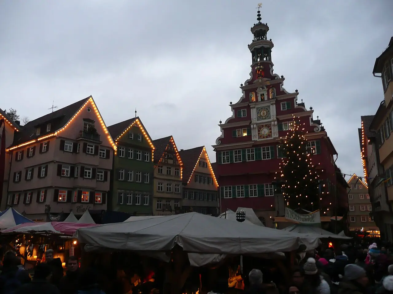 Old Town Hall with an illuminated Christmas tree, tents of the medieval market in front, at dusk