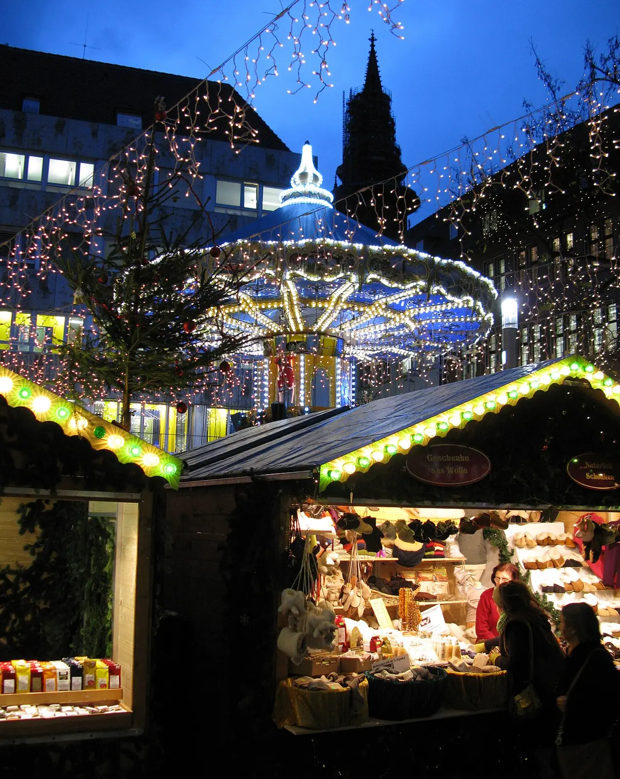 Carousel and stalls on Kartoffelmarkt at the blue hour, the Minster tower behind