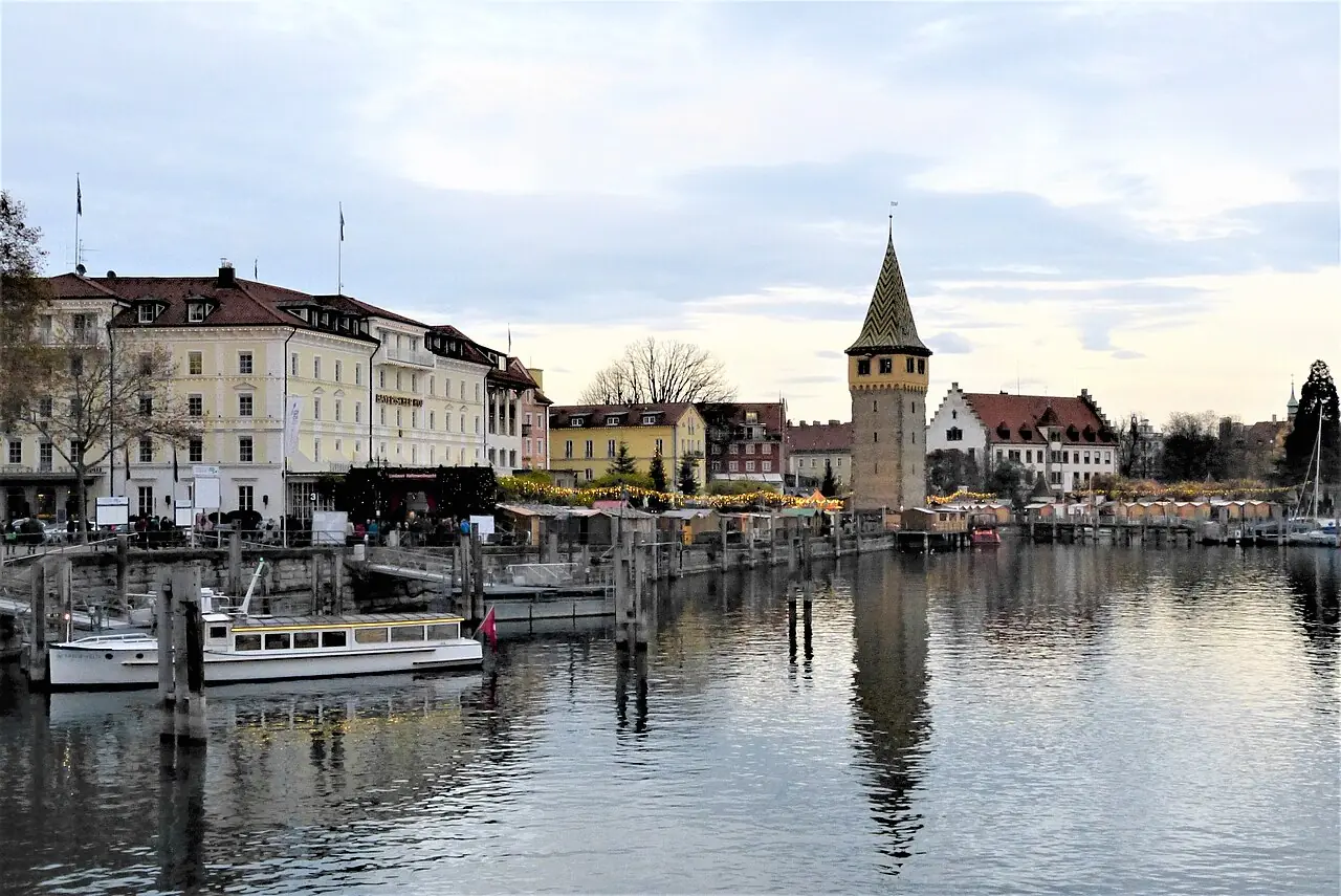 Lindau harbour with the Mangturm at dusk, with the huts of the Hafenweihnacht on the shore