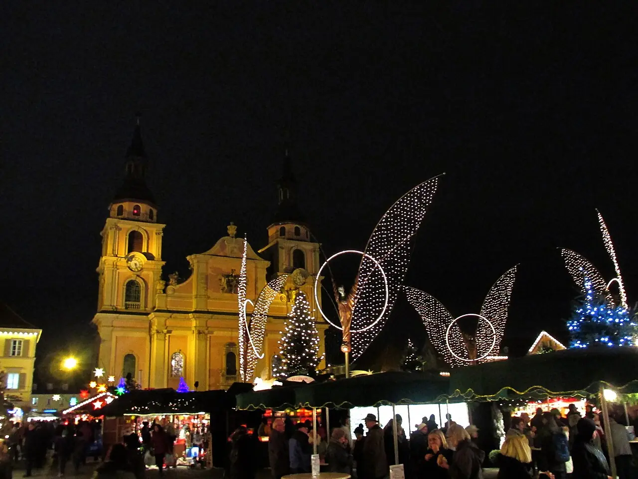 Protestant town church and glowing angel figures above the stalls on the Marktplatz, at night