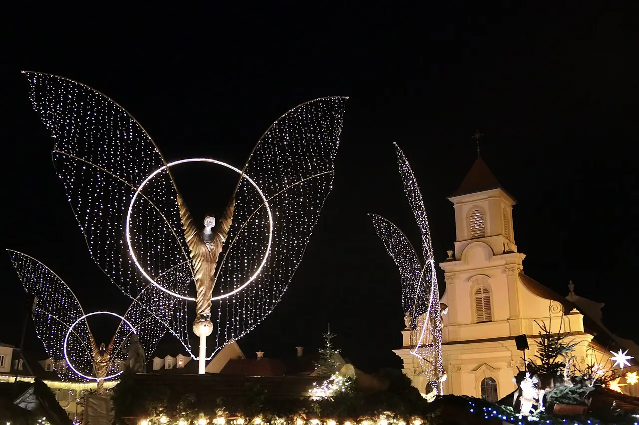 Angel figure with wings of light in front of the Catholic church on the Marktplatz, at night