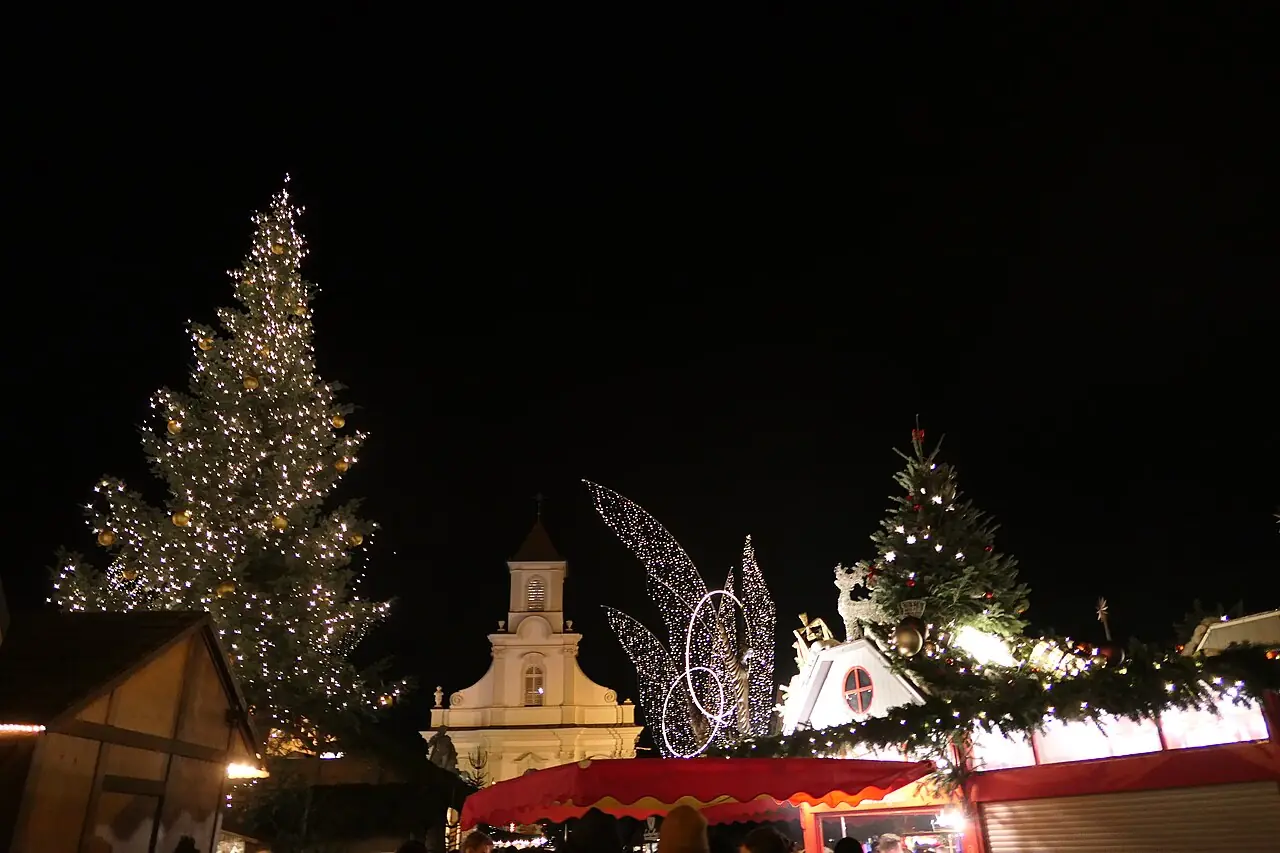 Christmas tree, Catholic church and decorated stall roofs at night