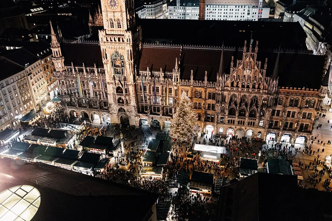View from the Alter Peter over the Christkindlmarkt on Marienplatz at night, with a Christmas tree in front of the New Town Hall