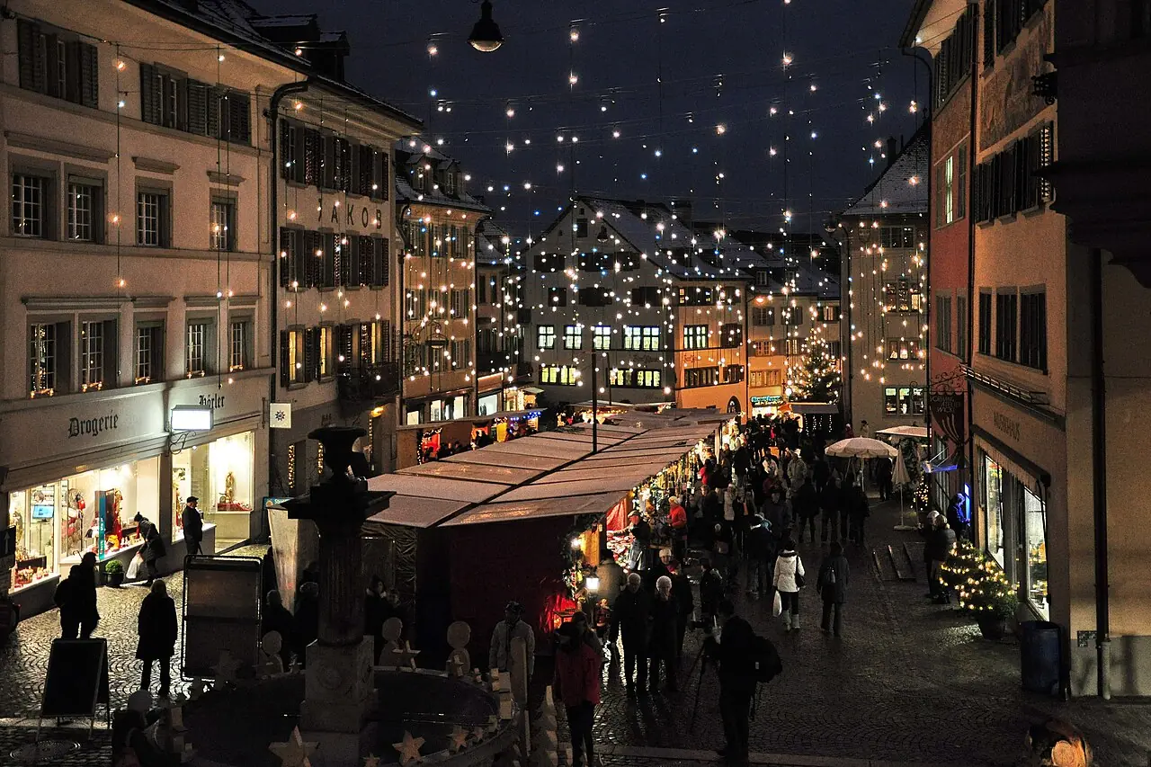 Row of market stalls under string lights on Hauptplatz, seen from above, in the evening (2010)