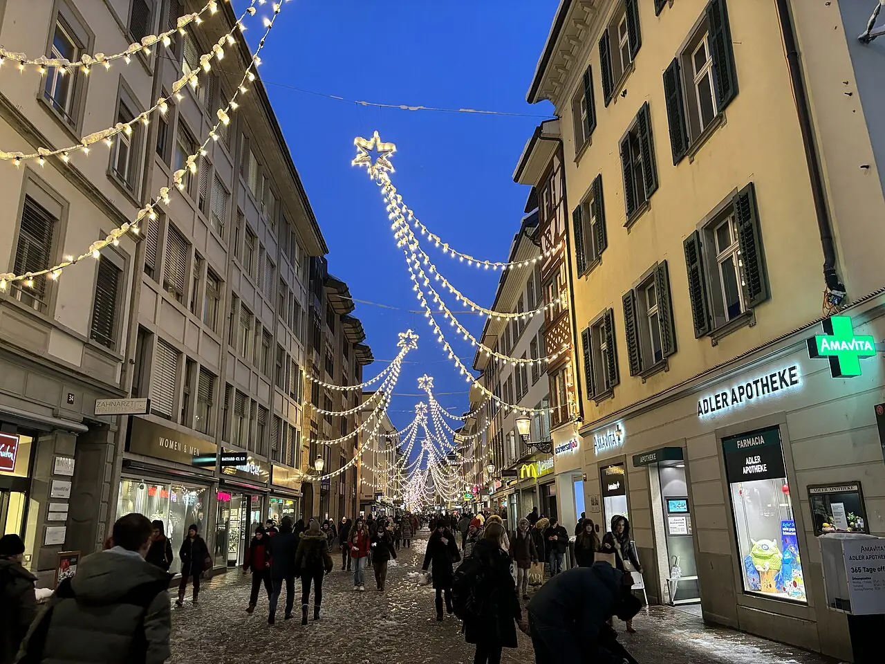 Strings of lights with stars above the Untertor lane in the old town, at dusk with remnants of snow (December 2023)