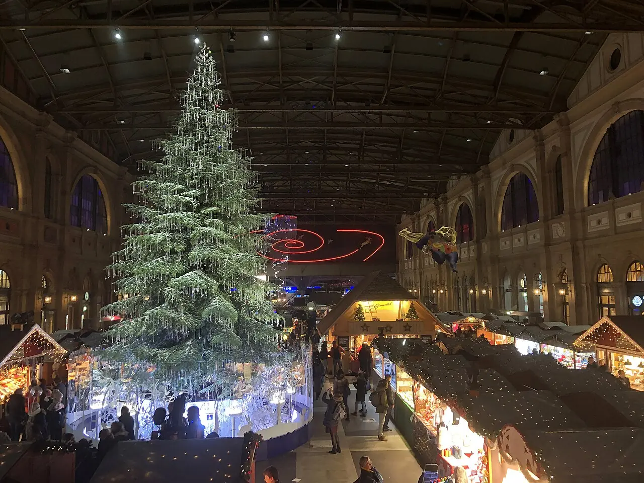 Christmas market in the concourse of Zurich HB seen from above, in the evening (2019, still with the Swarovski tree at the time; today the Lindt tree stands there)