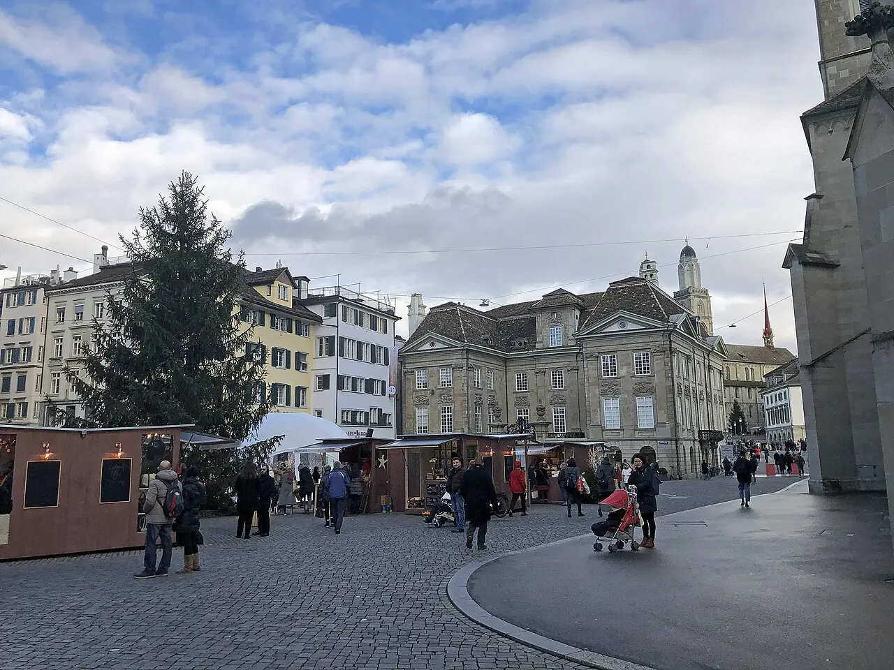 Market huts and Christmas tree on the Münsterhof by day, the Fraumünster on the right, the Grossmünster behind (2019)