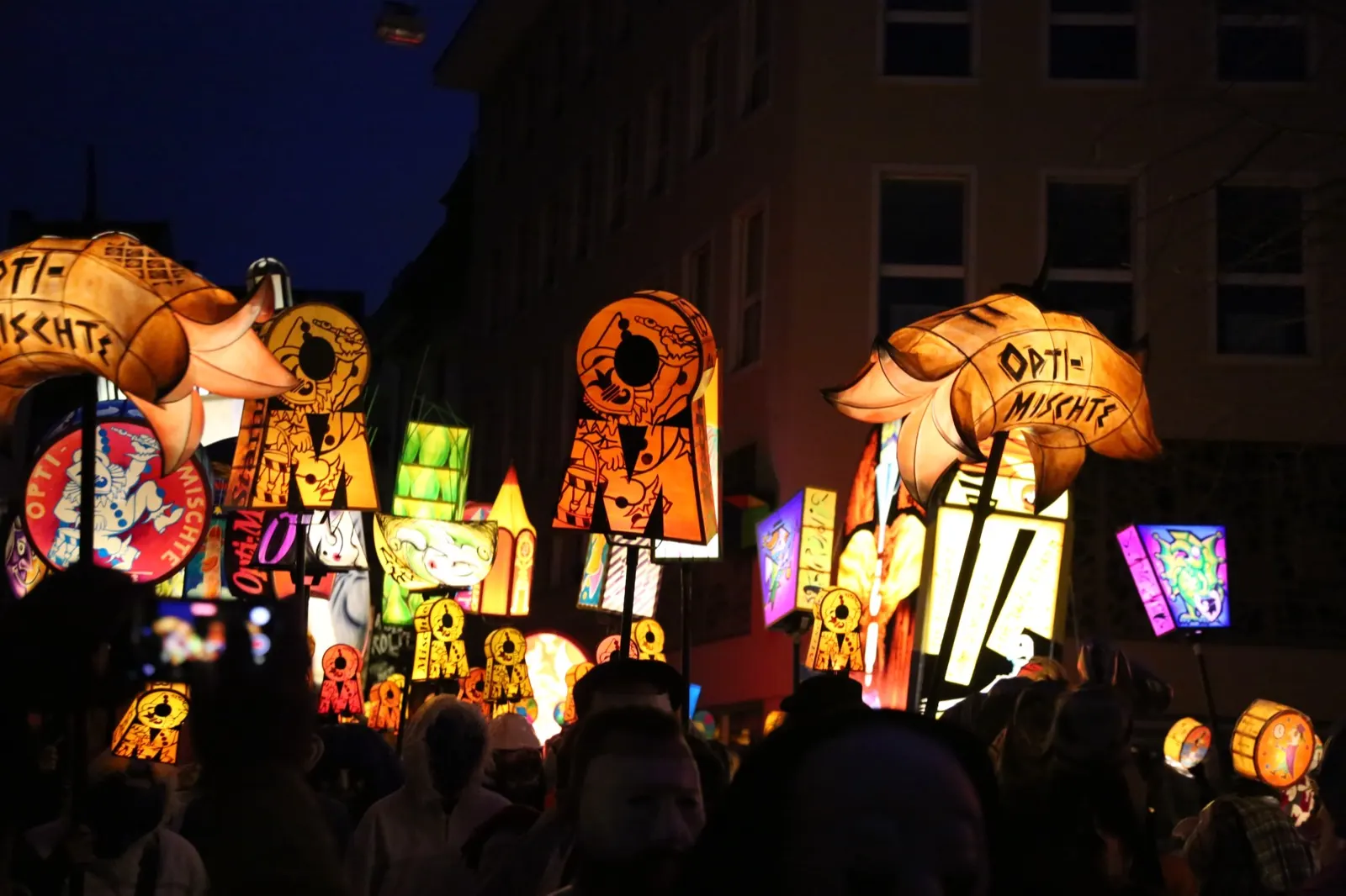 Leuchtende Laternen einer Clique im Morgengrauen am Morgestraich der Basler Fasnacht